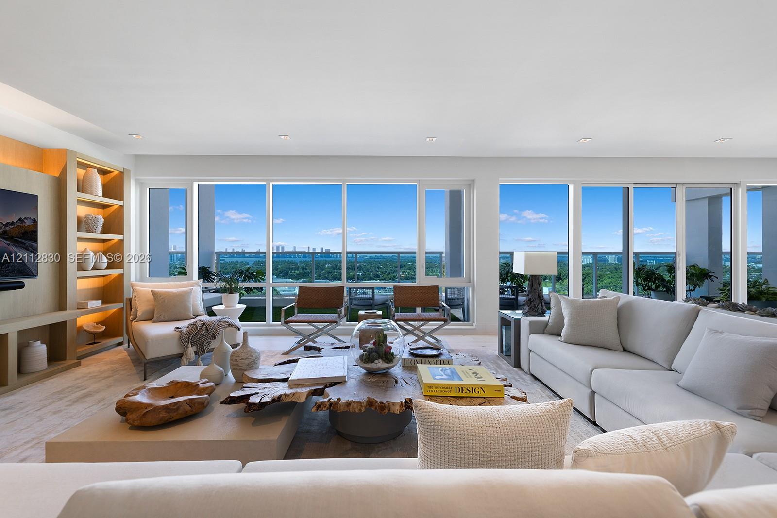 Living area featuring expansive floor-to-ceiling windows, integrated wall cabinetry with recessed shelving, and wood-finish flooring Living area featuring expansive floor-to-ceiling windows, integrated wall cabinetry with recessed shelving, and wood-finish flooring