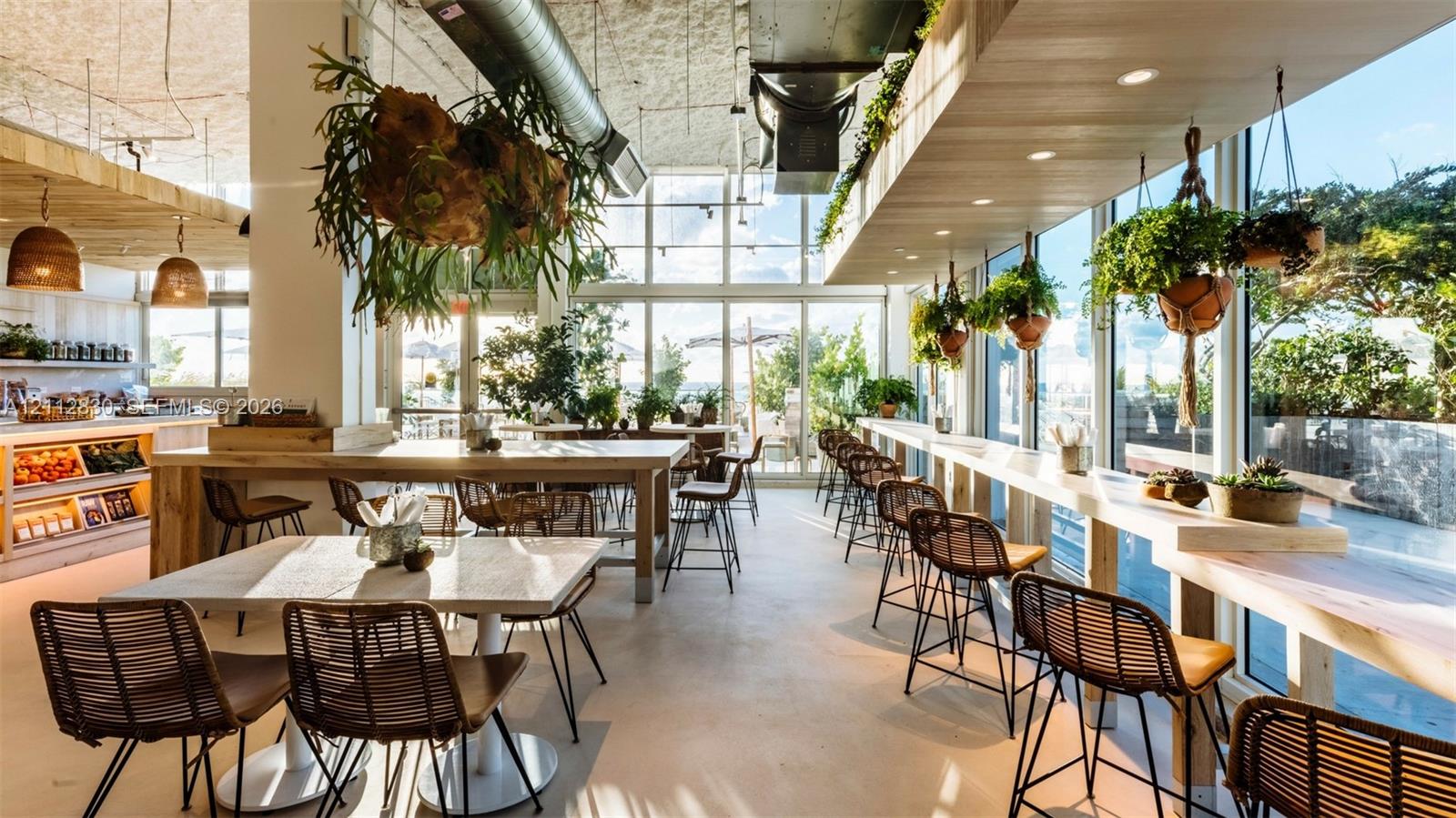 Expansive interior featuring floor-to-ceiling glass walls, exposed structural ductwork, custom light-toned wood-finish countertops, and recessed ceiling lighting