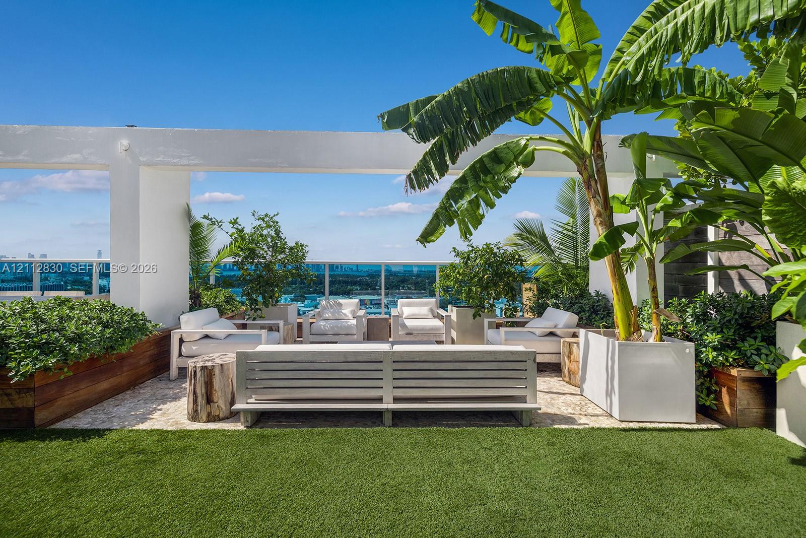 Rooftop terrace featuring artificial turf, built-in wooden planters, glass railings, and a structural pergola