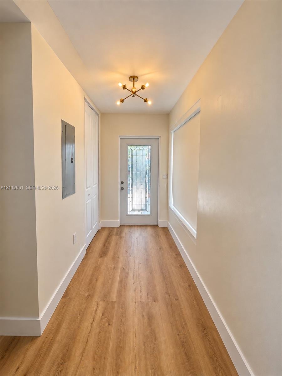 Entryway featuring wood-finish flooring, a multi-pane glass insert door, a modern sputnik-style flush-mount light fixture, and a built-in closet with paneled doors Entryway featuring wood-finish flooring, a multi-pane glass insert door, a modern sputnik-style flush-mount light fixture, and a built-in closet with paneled doors