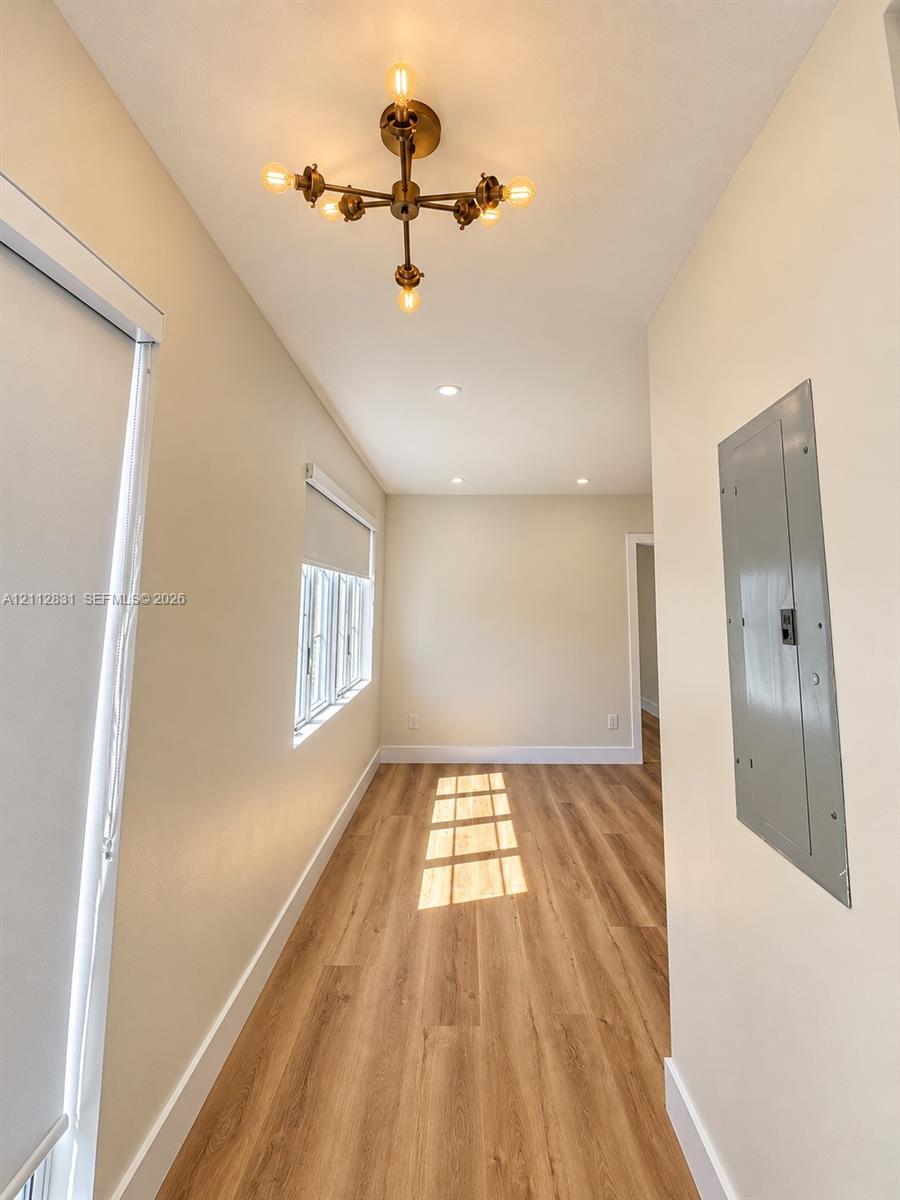 Wood-finish flooring, multi-light metallic chandelier, recessed ceiling lighting, and windows featuring roller shades Wood-finish flooring, multi-light metallic chandelier, recessed ceiling lighting, and windows featuring roller shades