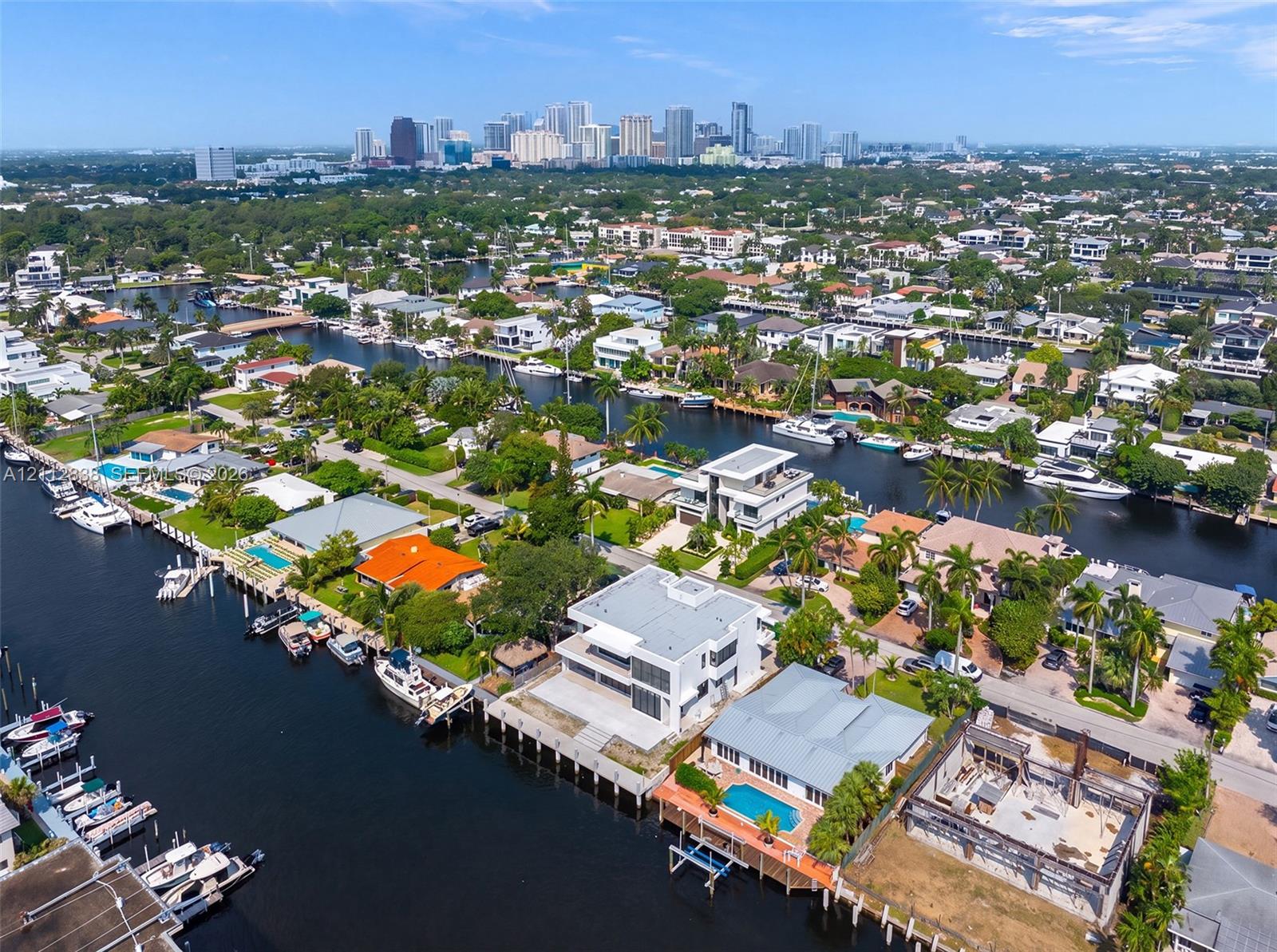 Aerial perspective of waterfront properties featuring deep-water canal access, private boat docks, and direct access to open water, set against a metropolitan skyline
