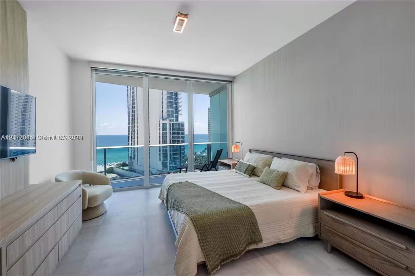 Floor-to-ceiling glass sliding doors, large-format tile flooring, built-in wall paneling, and an integrated balcony with glass railing