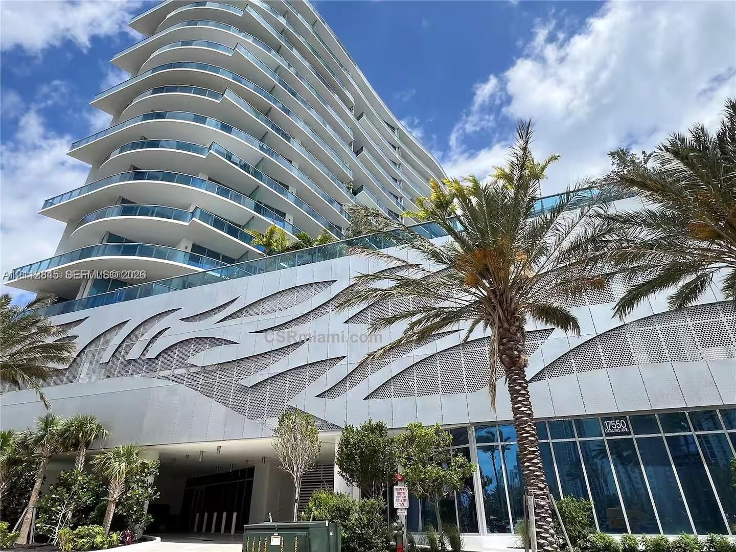 High-rise architectural exterior featuring tiered glass balconies, metallic geometric facade paneling, floor-to-ceiling glass windows, and mature palm landscaping