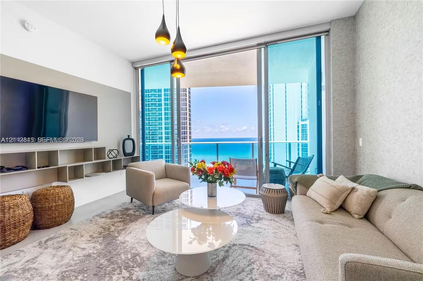 Floor-to-ceiling glass doors, custom built-in cabinetry, modern pendant lighting, textured wall finish, and a glass-paneled balcony Floor-to-ceiling glass doors, custom built-in cabinetry, modern pendant lighting, textured wall finish, and a glass-paneled balcony