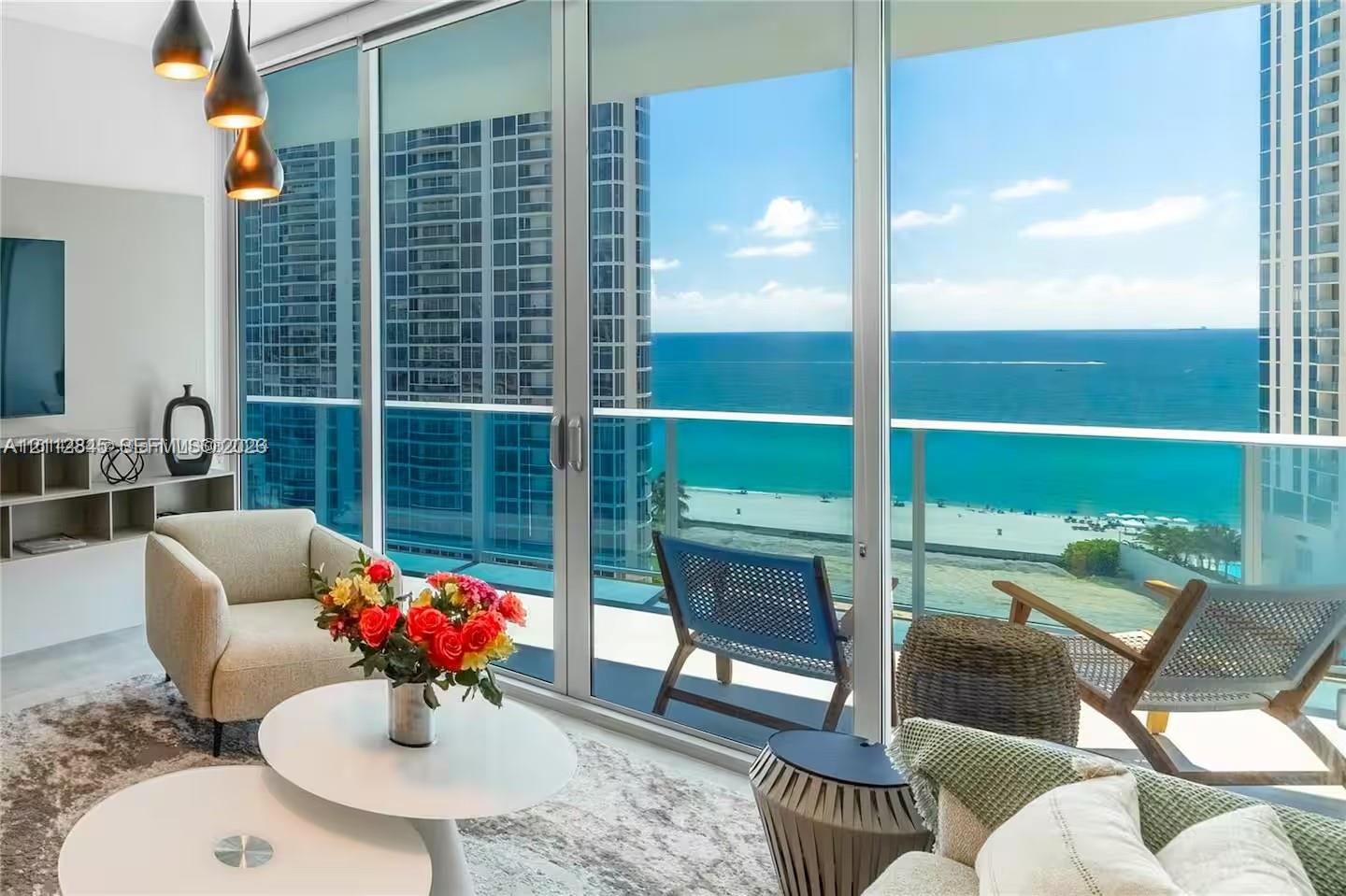 Floor-to-ceiling glass walls, expansive balcony with glass railings, built-in media shelving, and trio of pendant light fixtures Floor-to-ceiling glass walls, expansive balcony with glass railings, built-in media shelving, and trio of pendant light fixtures