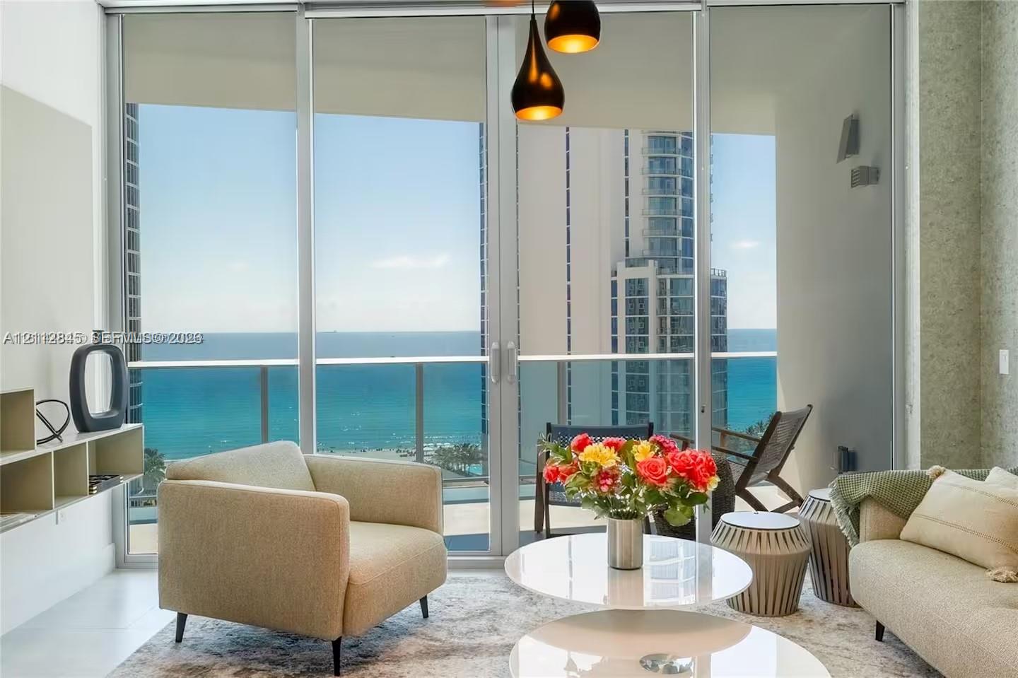 Floor-to-ceiling glass sliding doors, private balcony with metal railing, pendant light fixture with tiered shades, and custom built-in shelving Floor-to-ceiling glass sliding doors, private balcony with metal railing, pendant light fixture with tiered shades, and custom built-in shelving