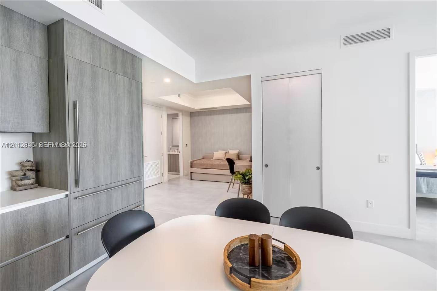 Modern kitchen cabinetry with wood-finish paneling, integrated refrigerator, white stone countertops, and tile flooring Modern kitchen cabinetry with wood-finish paneling, integrated refrigerator, white stone countertops, and tile flooring