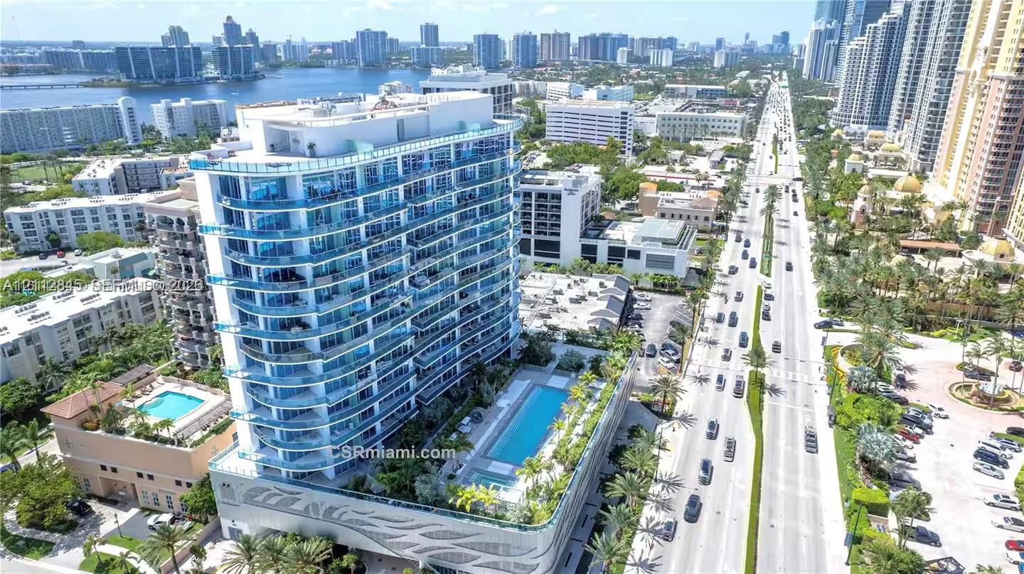 High-rise residential building featuring a glass facade, expansive wrap-around balconies, a structured podium base with decorative relief, and a recreational deck containing a swimming pool