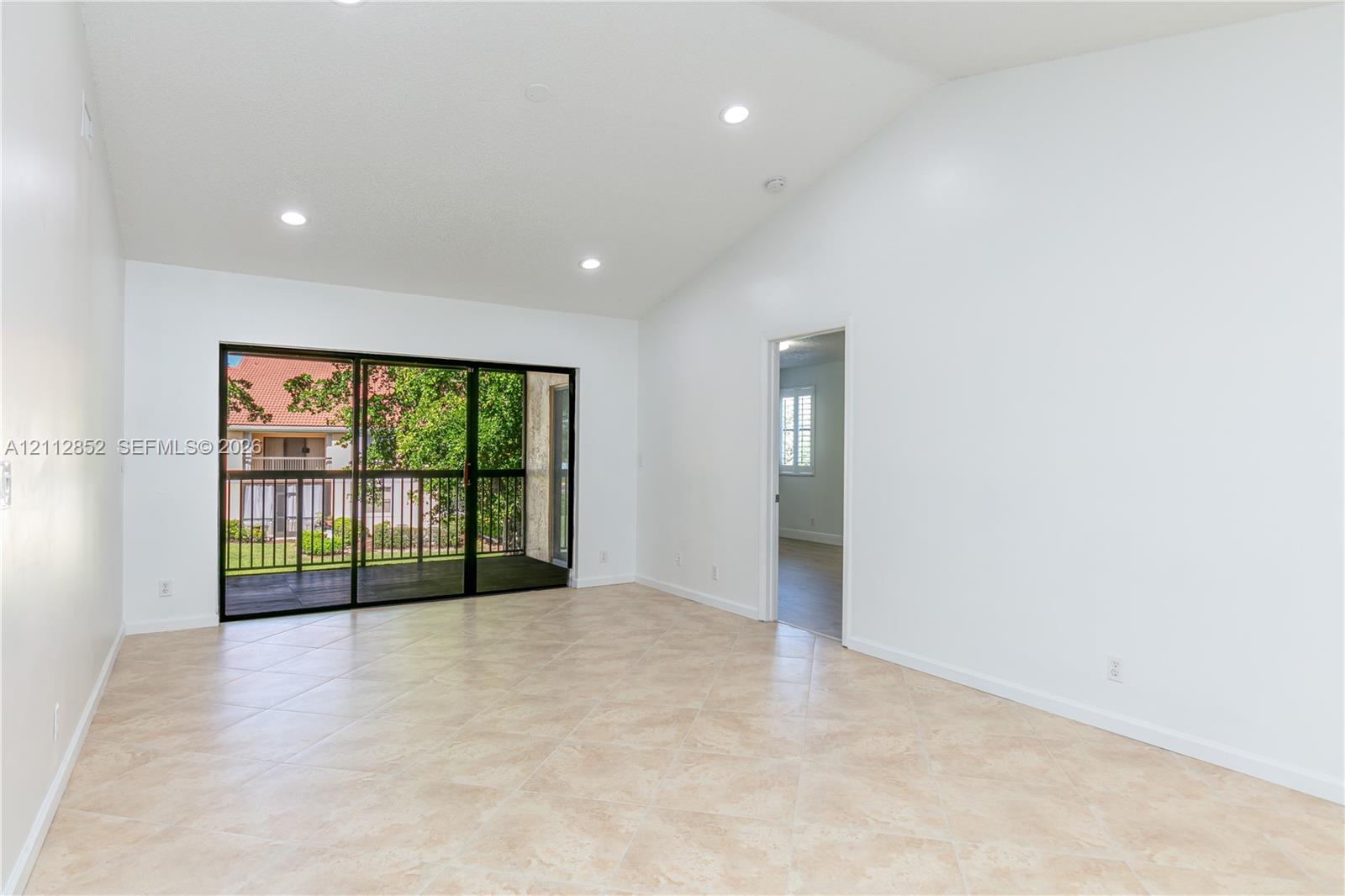 Vaulted ceilings, recessed lighting, tile flooring, and large sliding glass doors providing access to a screened balcony