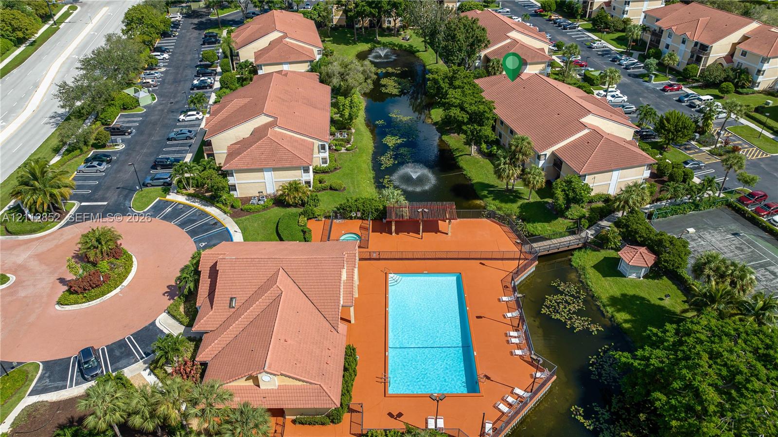 Aerial perspective of a multi-unit complex featuring a swimming pool, spa, pond with fountain features, and landscaped grounds