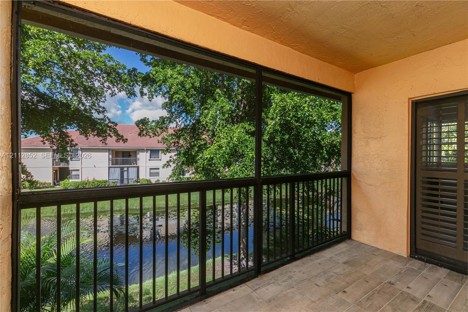 Screened-in balcony featuring wood-finish flooring, metal railing, and direct water exposure