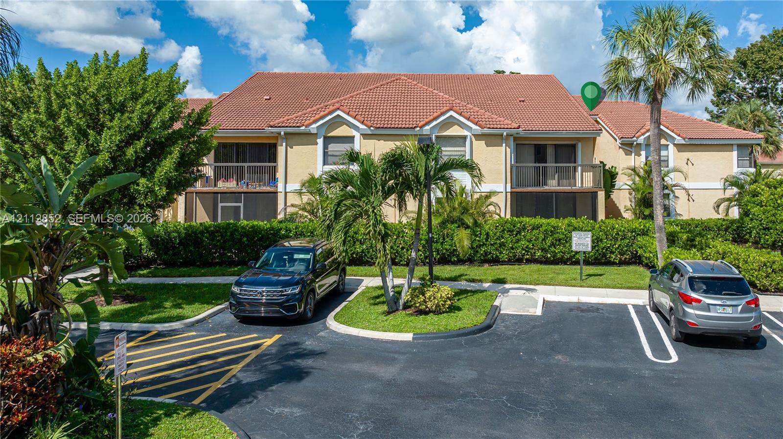 Multi-family exterior featuring a terracotta-tiled roof, private second-story balconies, and landscaped grounds with mature palm trees Multi-family exterior featuring a terracotta-tiled roof, private second-story balconies, and landscaped grounds with mature palm trees