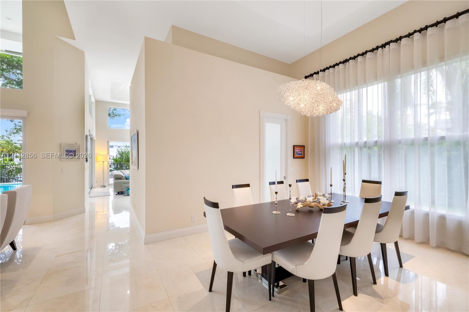High ceilings, polished stone flooring, custom architectural pendant lighting, and oversized windows with drapery