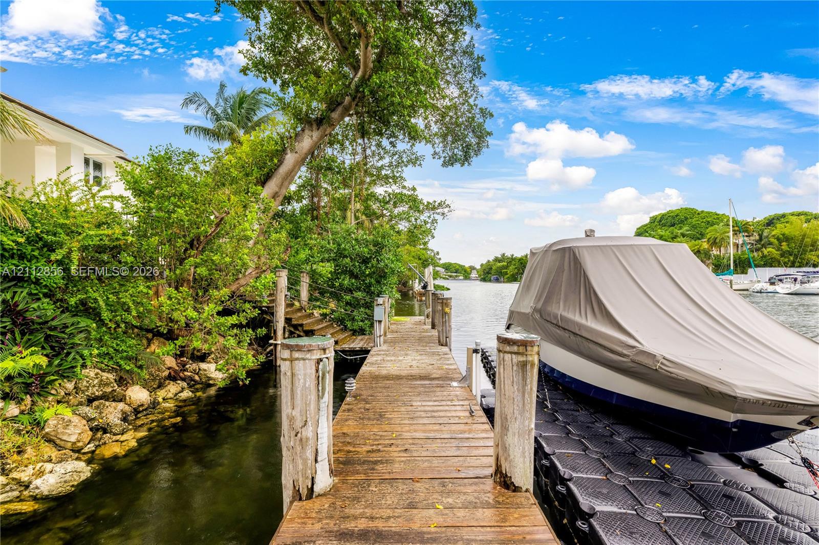Waterfront dock featuring a wood-plank pier, stone-lined shoreline, and floating docking platform