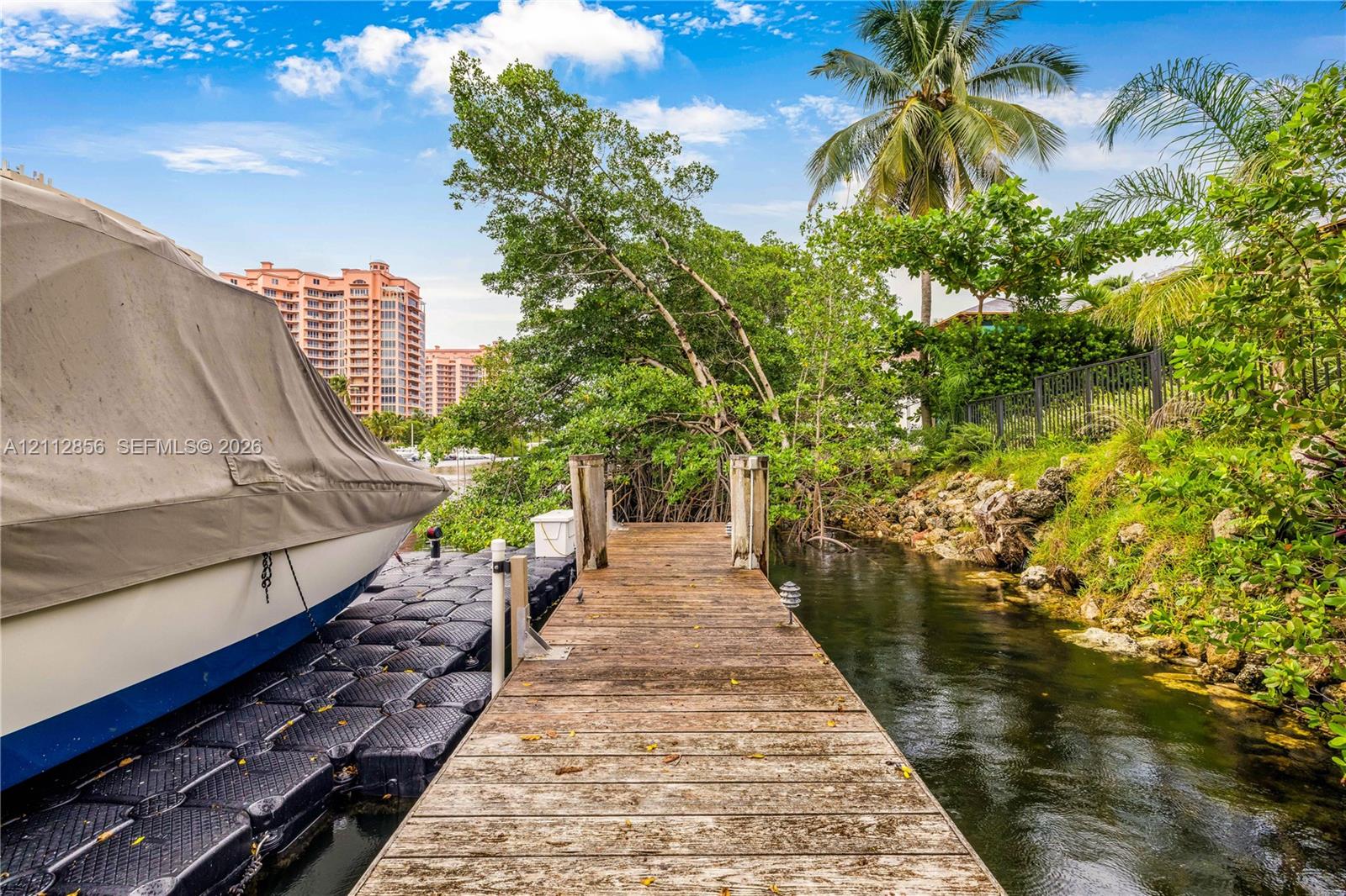 Wood-plank dock featuring modular floating side sections, stone embankment, and metal perimeter fencing