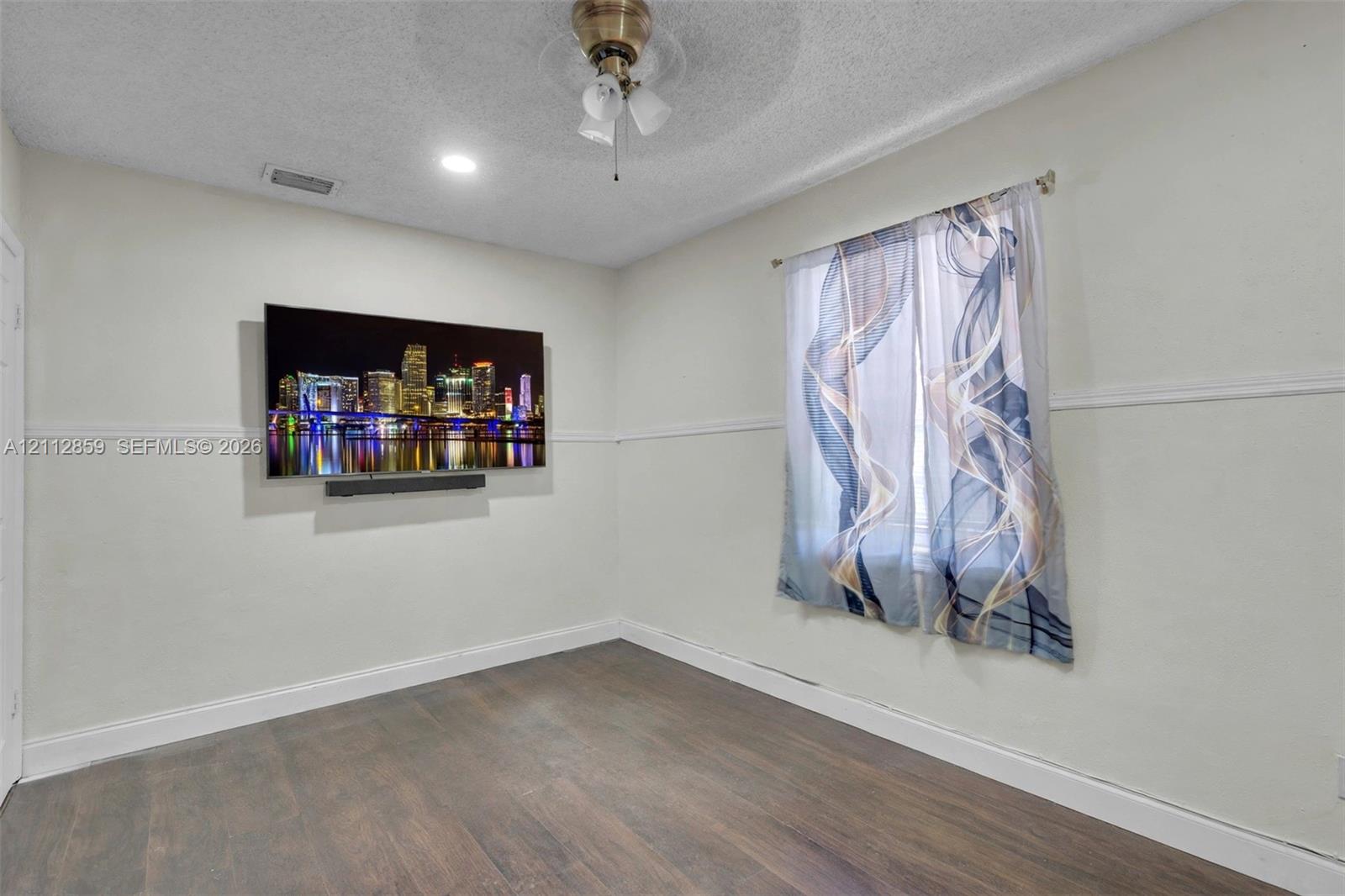 Room featuring wood-finish flooring, a ceiling fan with integrated lighting, a recessed ceiling light, and horizontal chair rail molding