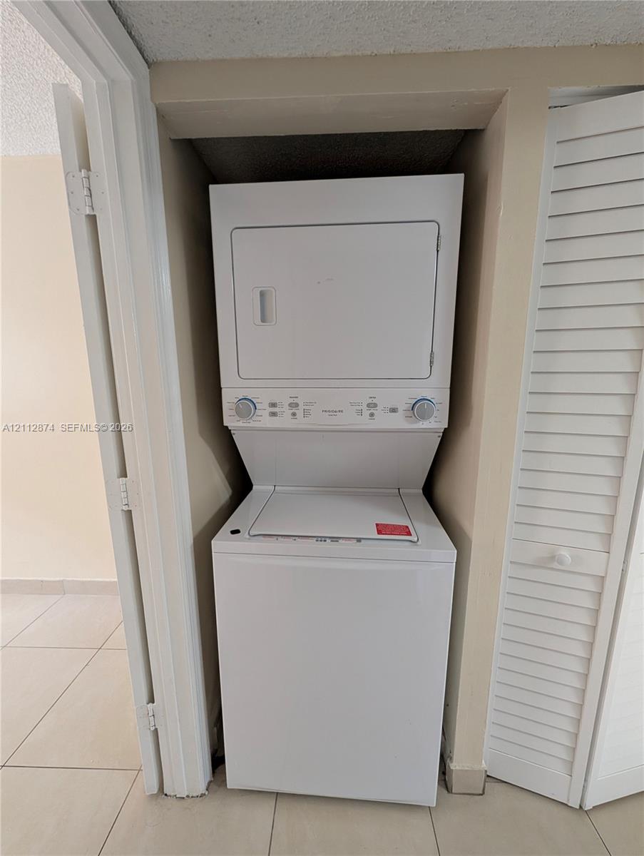 Stacked laundry unit with white finish housed in a dedicated closet space with louvered bi-fold doors