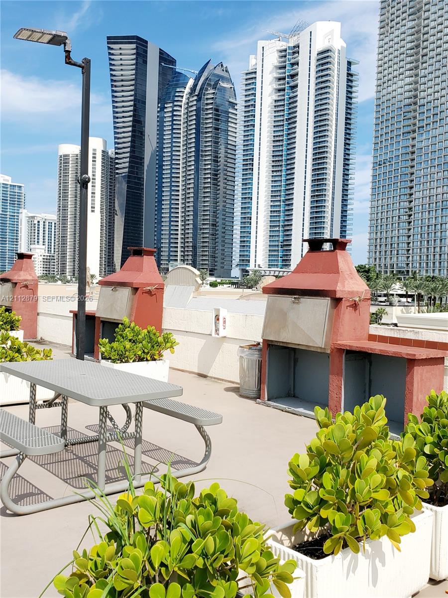Outdoor terrace featuring multiple built-in masonry grilling stations, integrated planters, and hardscape flooring Outdoor terrace featuring multiple built-in masonry grilling stations, integrated planters, and hardscape flooring