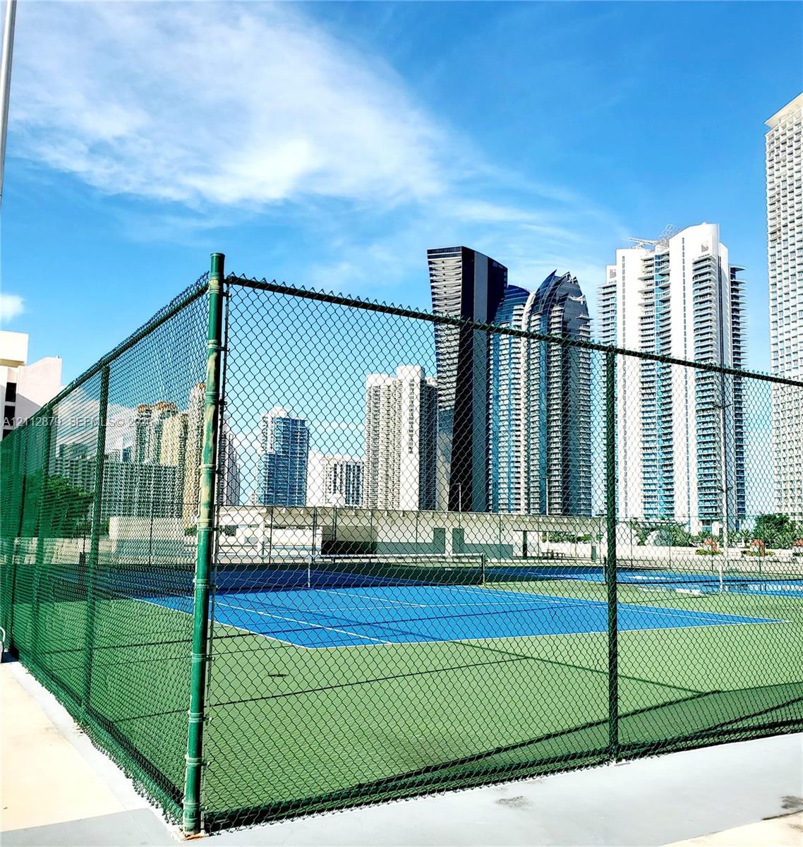 Tennis court featuring a high-tension perimeter chain-link fence, hard-surface multi-tone blue and green court markings, and integrated net system Tennis court featuring a high-tension perimeter chain-link fence, hard-surface multi-tone blue and green court markings, and integrated net system