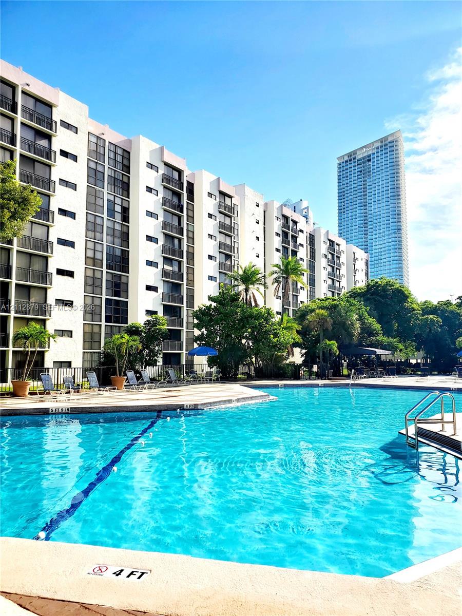 Swimming pool with concrete decking, surrounding palm trees, and multi-story building featuring private balconies Swimming pool with concrete decking, surrounding palm trees, and multi-story building featuring private balconies
