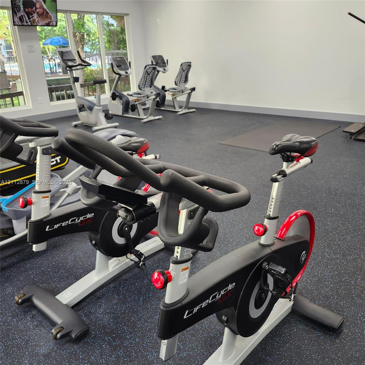 Fitness room featuring durable rubber flooring, large floor-to-ceiling windows, and integrated stationary exercise equipment Fitness room featuring durable rubber flooring, large floor-to-ceiling windows, and integrated stationary exercise equipment