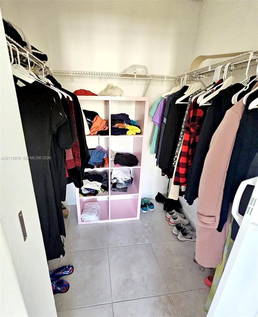 Walk-in storage space featuring large-format ceramic floor tiling and perimeter wire shelving