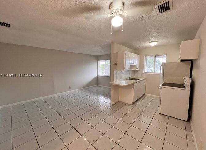 Kitchen featuring white cabinetry, a peninsula counter, and tile flooring throughout