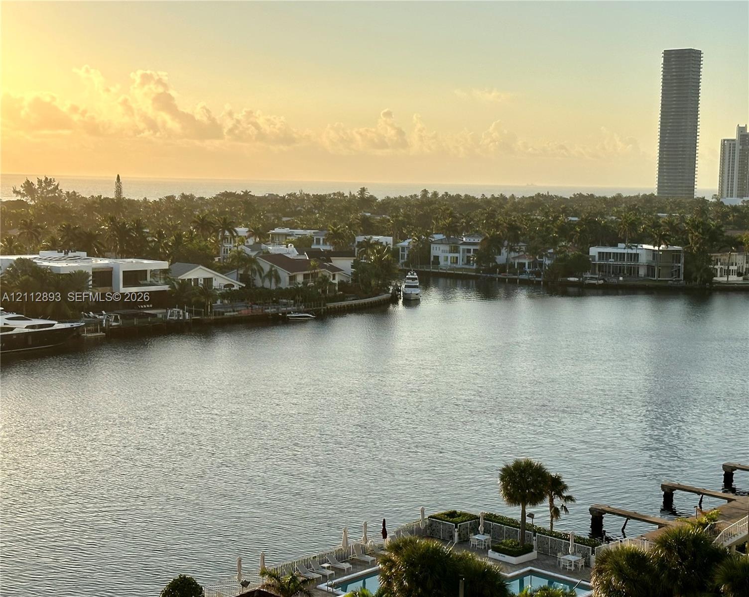 Waterfront panorama featuring a canal-side swimming pool, multi-level docks, and a backdrop of coastal skyline
