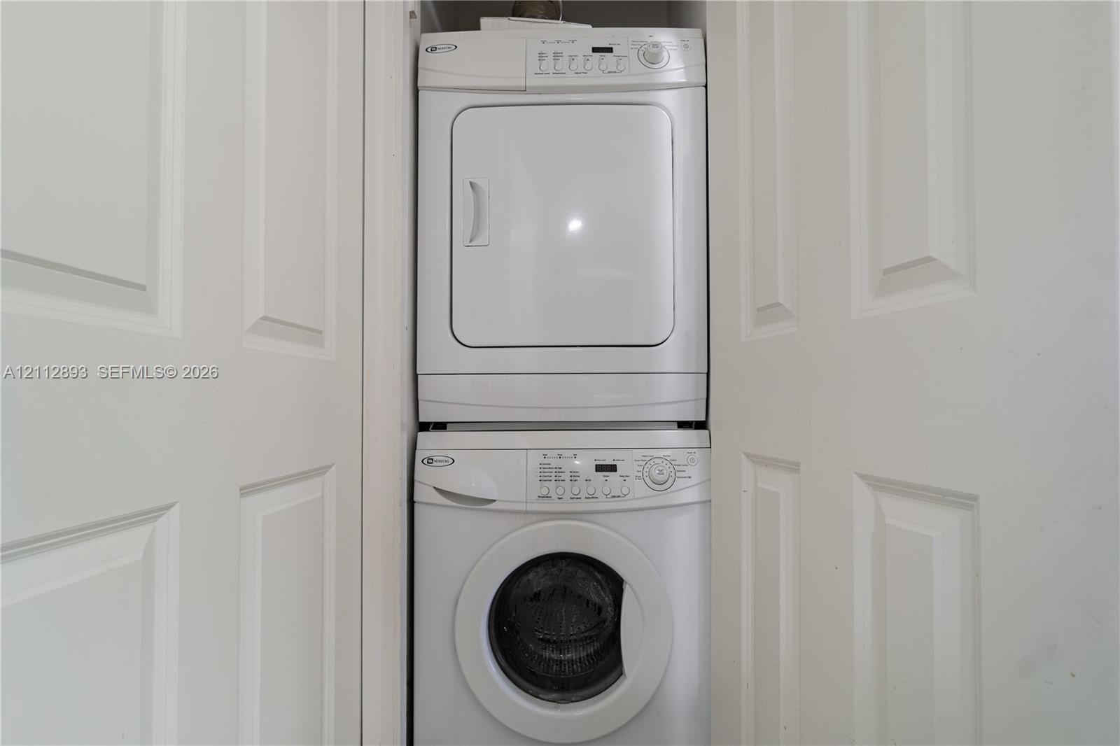 Stackable laundry unit featuring a white front-loading washing machine and a matching dryer, enclosed by white paneled closet doors