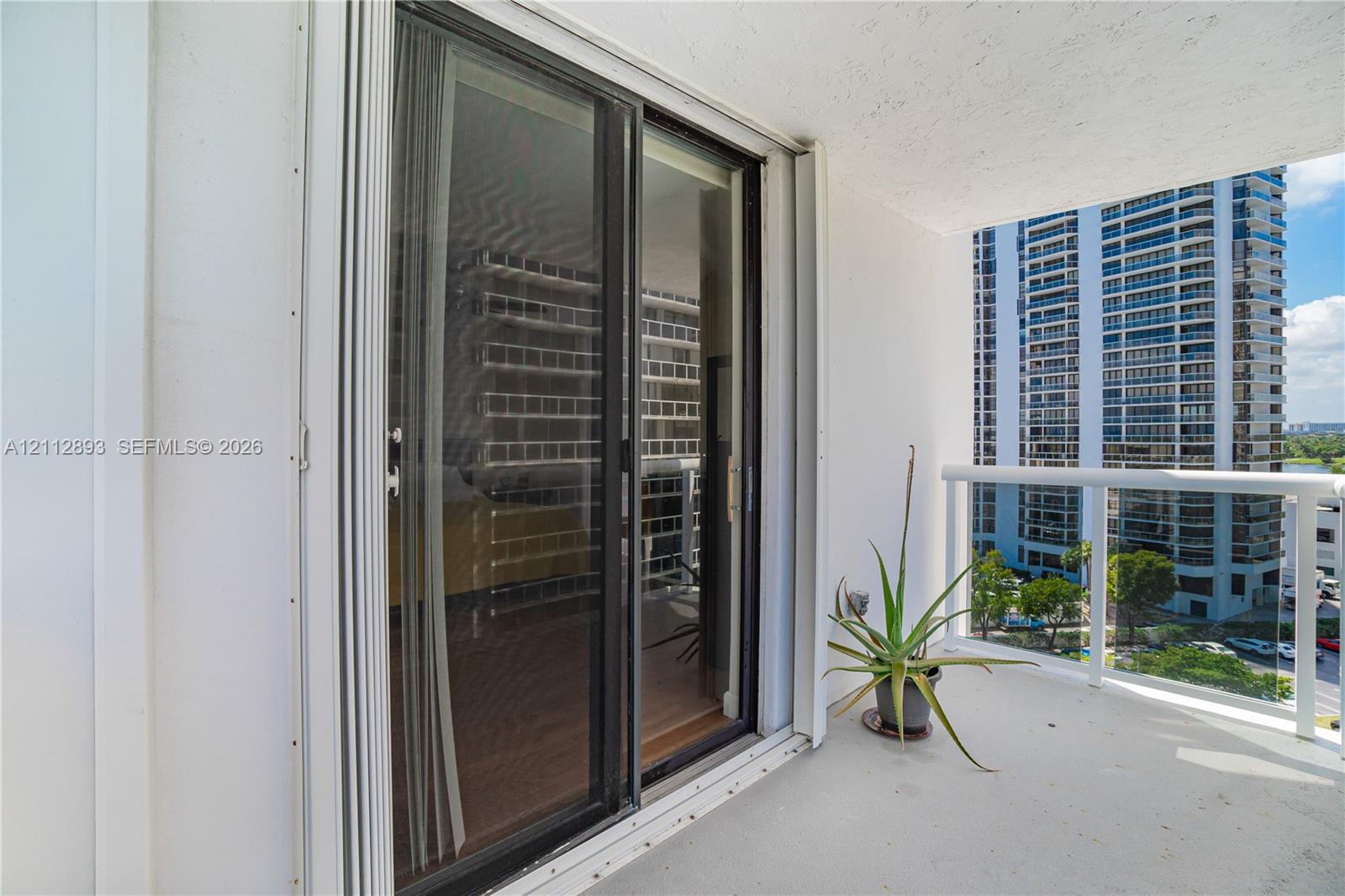 Covered balcony featuring a white metal railing and sliding glass door entrance