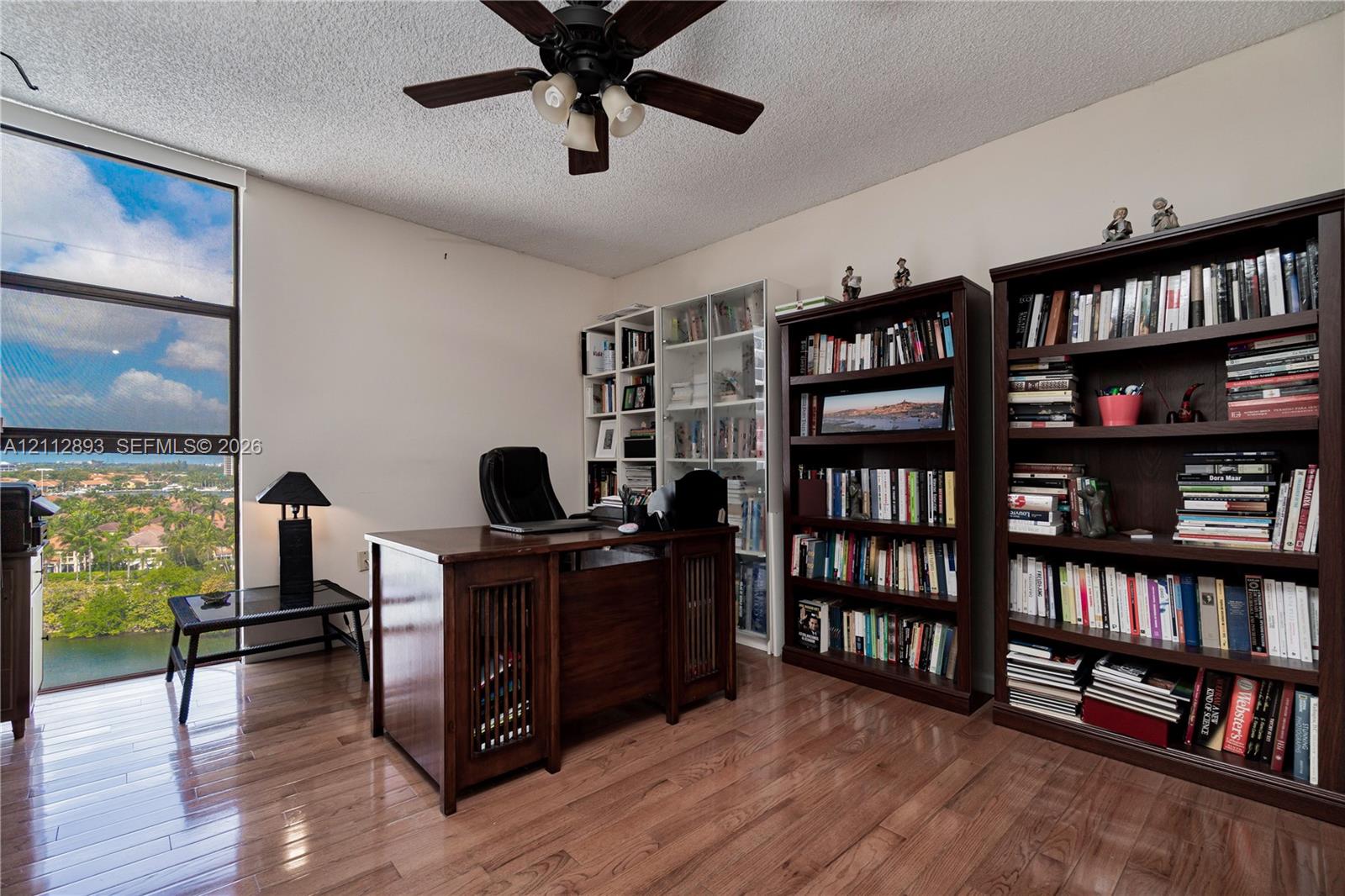 Floor-to-ceiling window featuring natural light, wood-finish flooring, and an attached ceiling fan with lighting