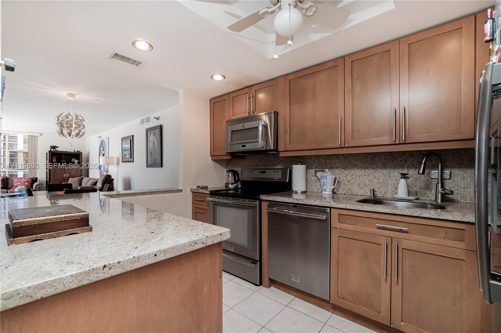 Kitchen featuring wood cabinetry, stone countertops, stainless steel appliances, tiled backsplash, and recessed lighting