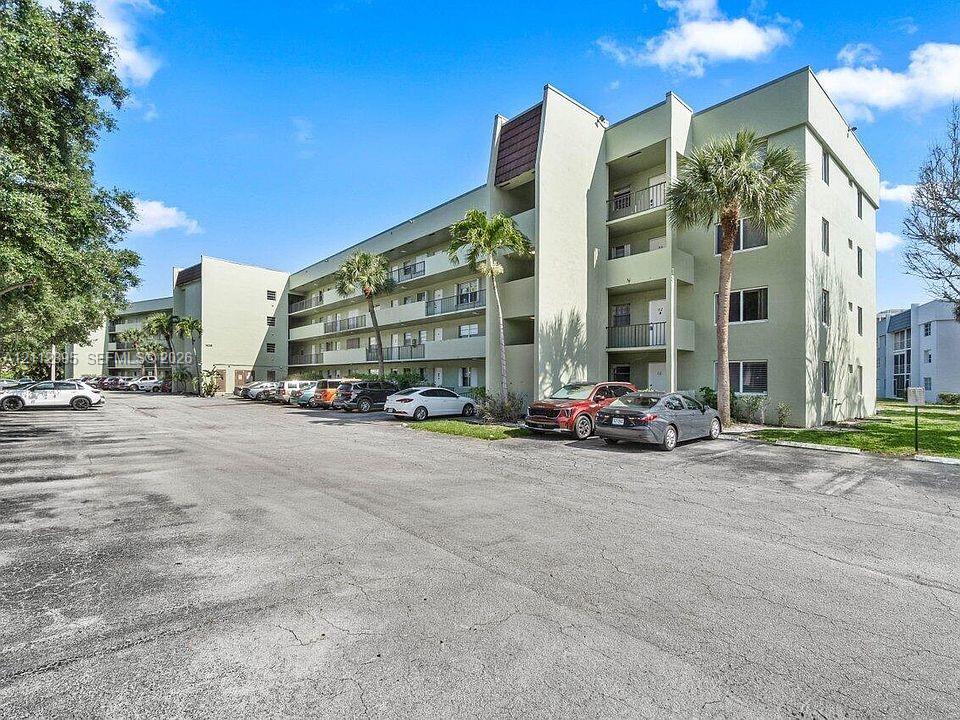 Multi-story exterior featuring concrete construction, recessed balconies, and integrated surface parking