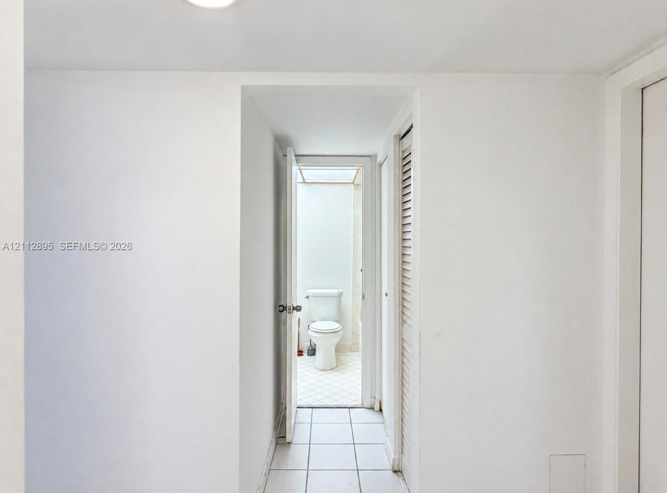 Ceramic tile flooring, louvered bi-fold doors, and a porcelain toilet fixture