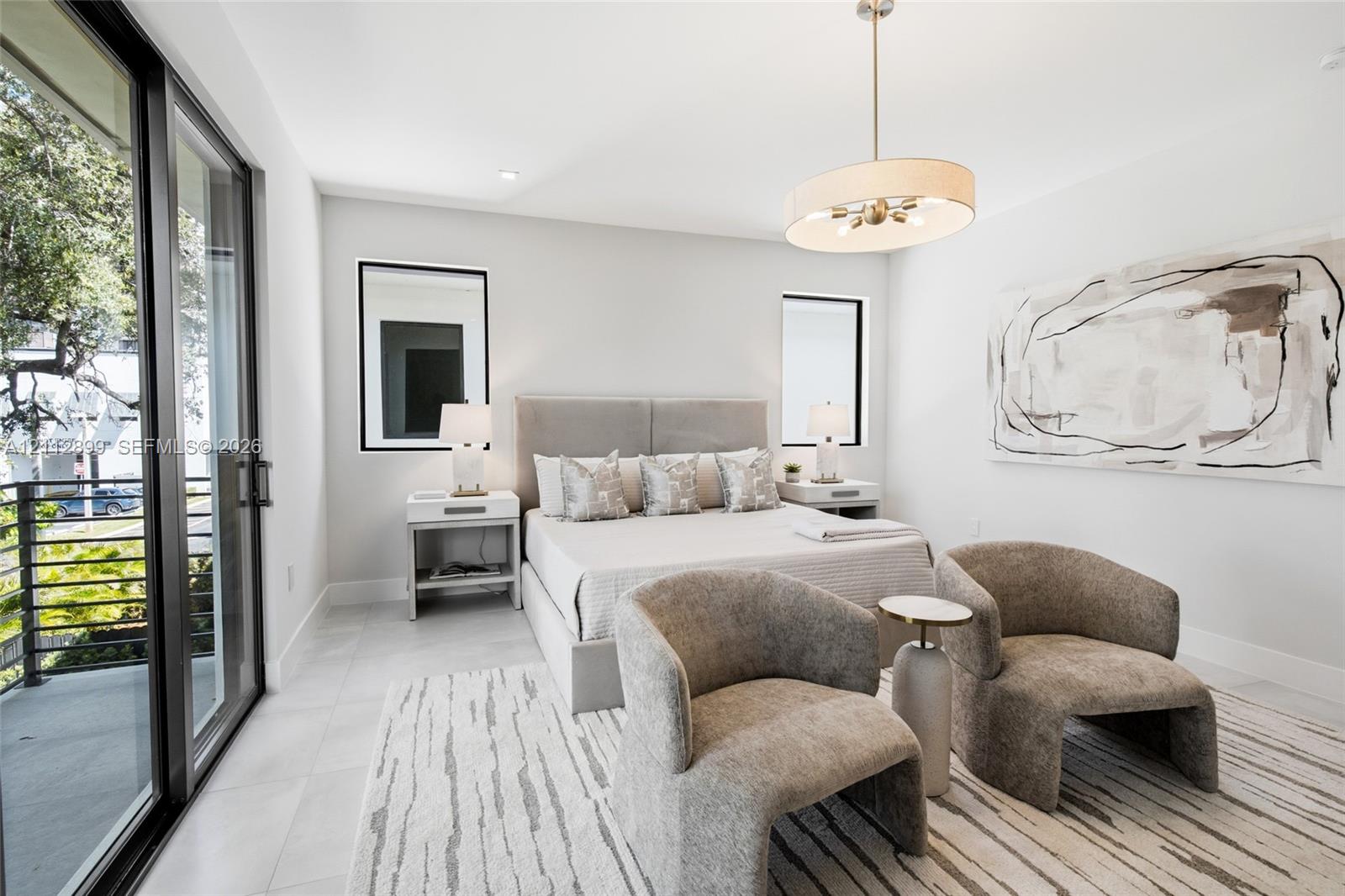 Neutral-toned room featuring large-format tile flooring, sliding glass door access to a balcony, recessed lighting, and a drum-style pendant fixture