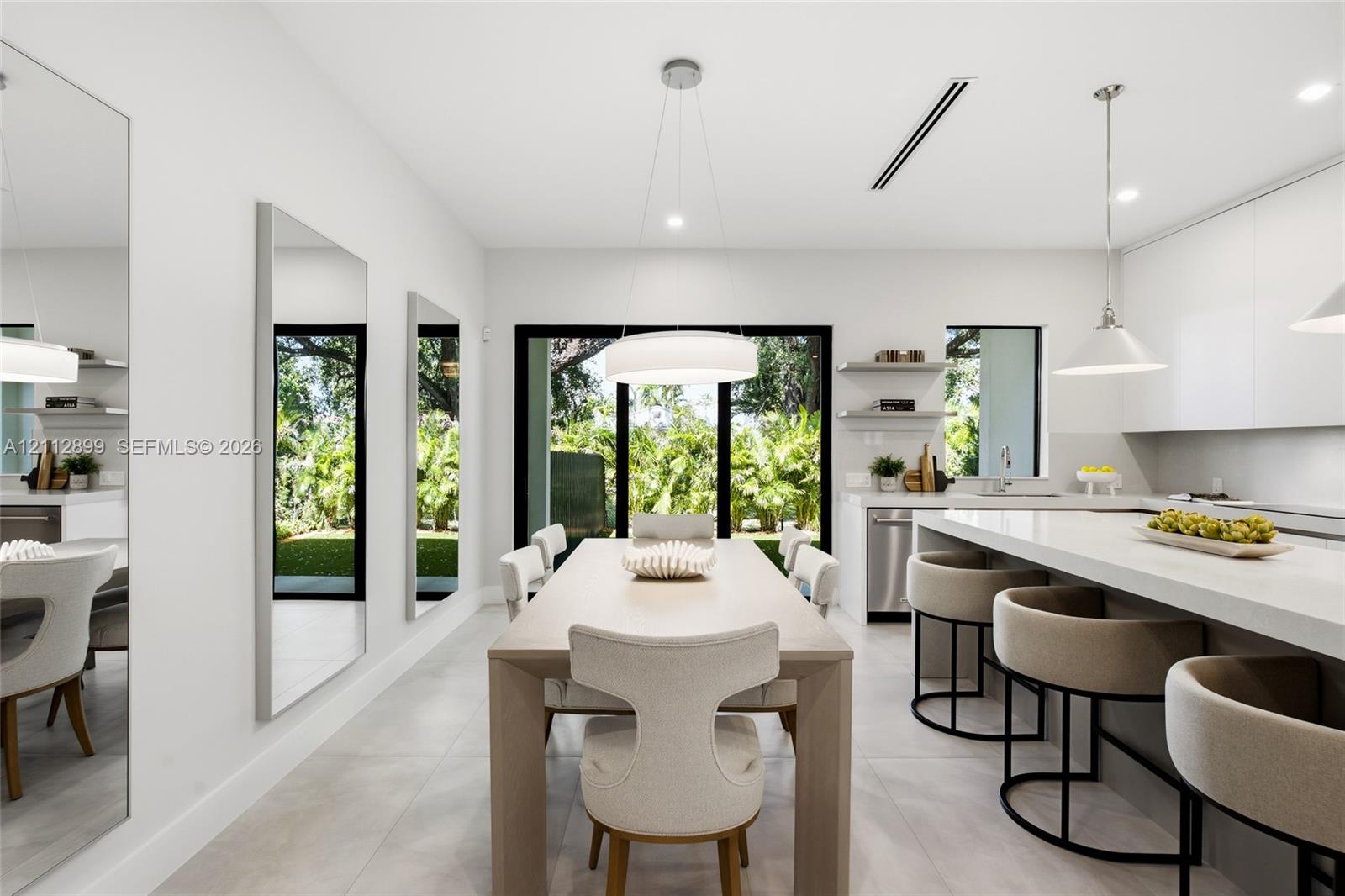 Modern kitchen featuring flat-panel cabinetry, a quartz waterfall island, large-format tile flooring, integrated linear lighting, and floor-to-ceiling glass sliding doors