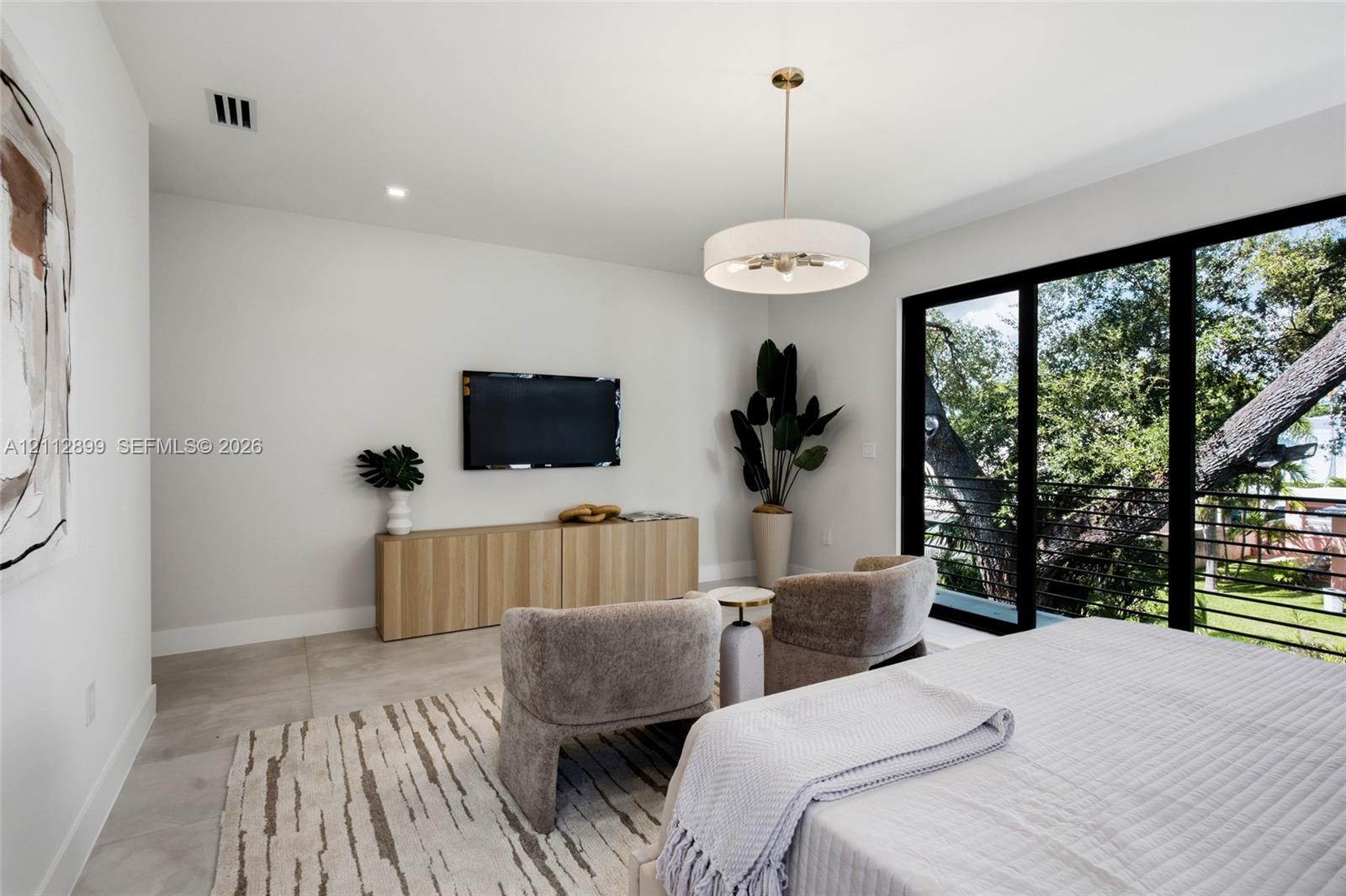 Large-format tile flooring, drum-style chandelier with metallic accents, built-in light-tone wood-finish cabinetry, and floor-to-ceiling sliding glass doors with metal railings