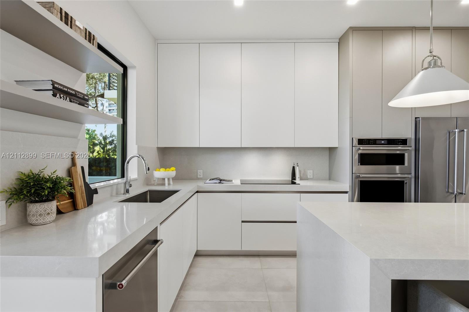 Modern kitchen featuring flat-panel cabinetry, light-toned stone countertops, built-in stainless steel appliances, dual open floating shelves, and an oversized island