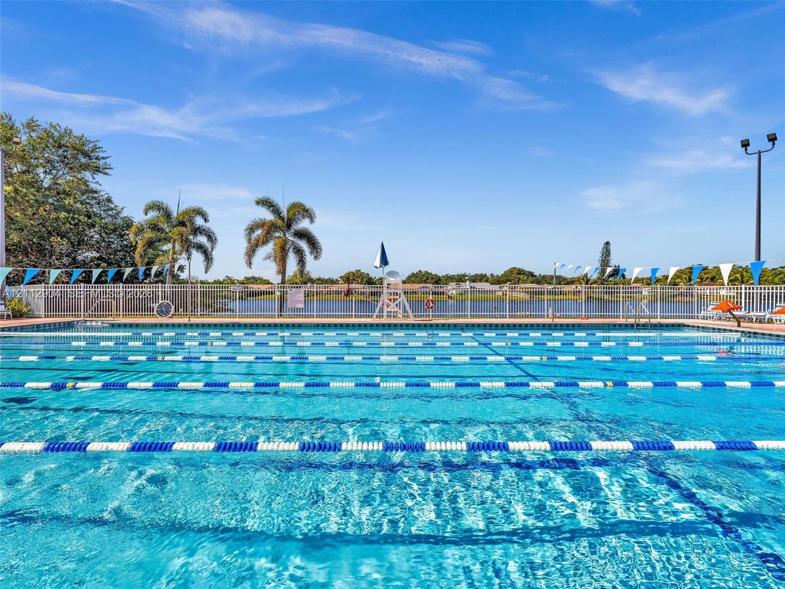 Lap swimming pool featuring marked lanes, surrounding perimeter fencing, and water frontage