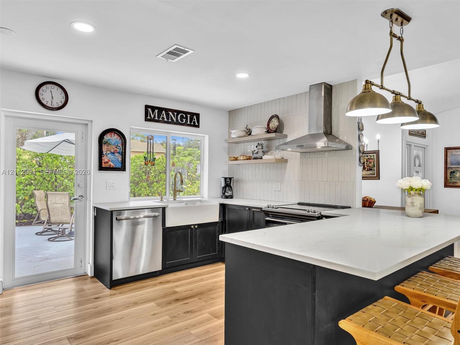 Kitchen featuring an expansive center island with stone countertop, stainless steel appliances, apron-front sink, vertical-tile backsplash, and open wood shelving