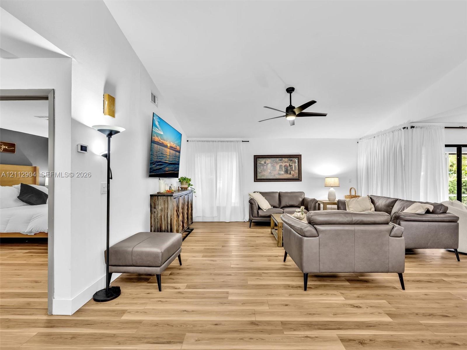 Living space featuring wood-finish flooring, high ceilings, and a multi-blade ceiling fan