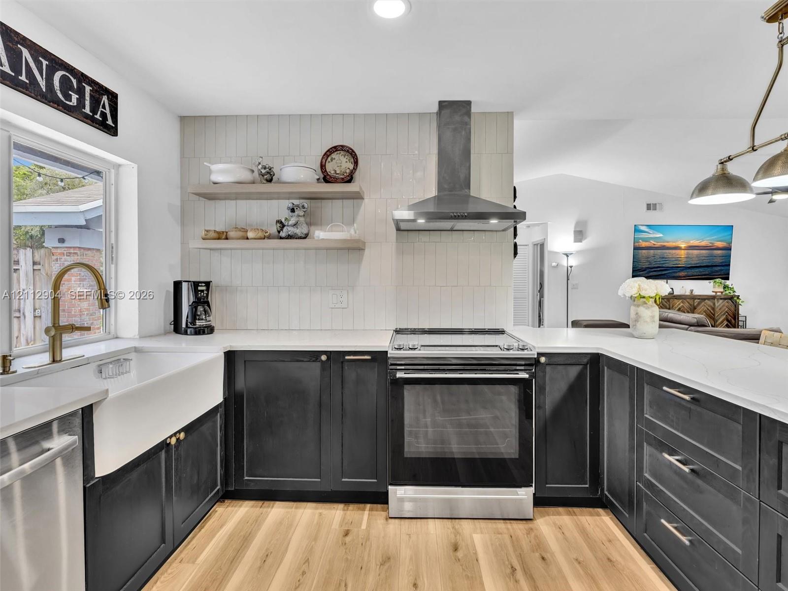 Kitchen featuring dark-finish cabinetry, white countertops, a deep apron-front sink, vertical-set wall tile backsplash, and wood-finish flooring