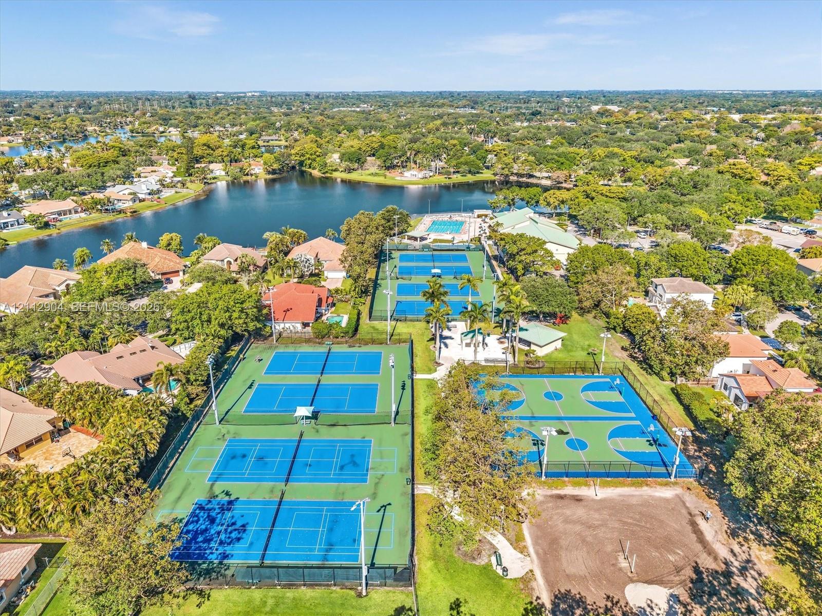 Recreational facility featuring multiple fenced tennis courts, a basketball court, and a swimming pool