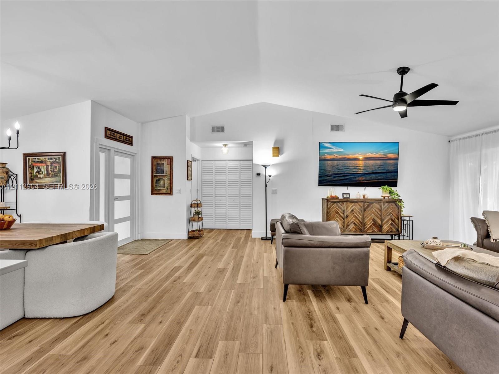 Vaulted ceilings, wood-finish flooring, matte black ceiling fan, multi-pane glass entry door, and folding louvered closet doors