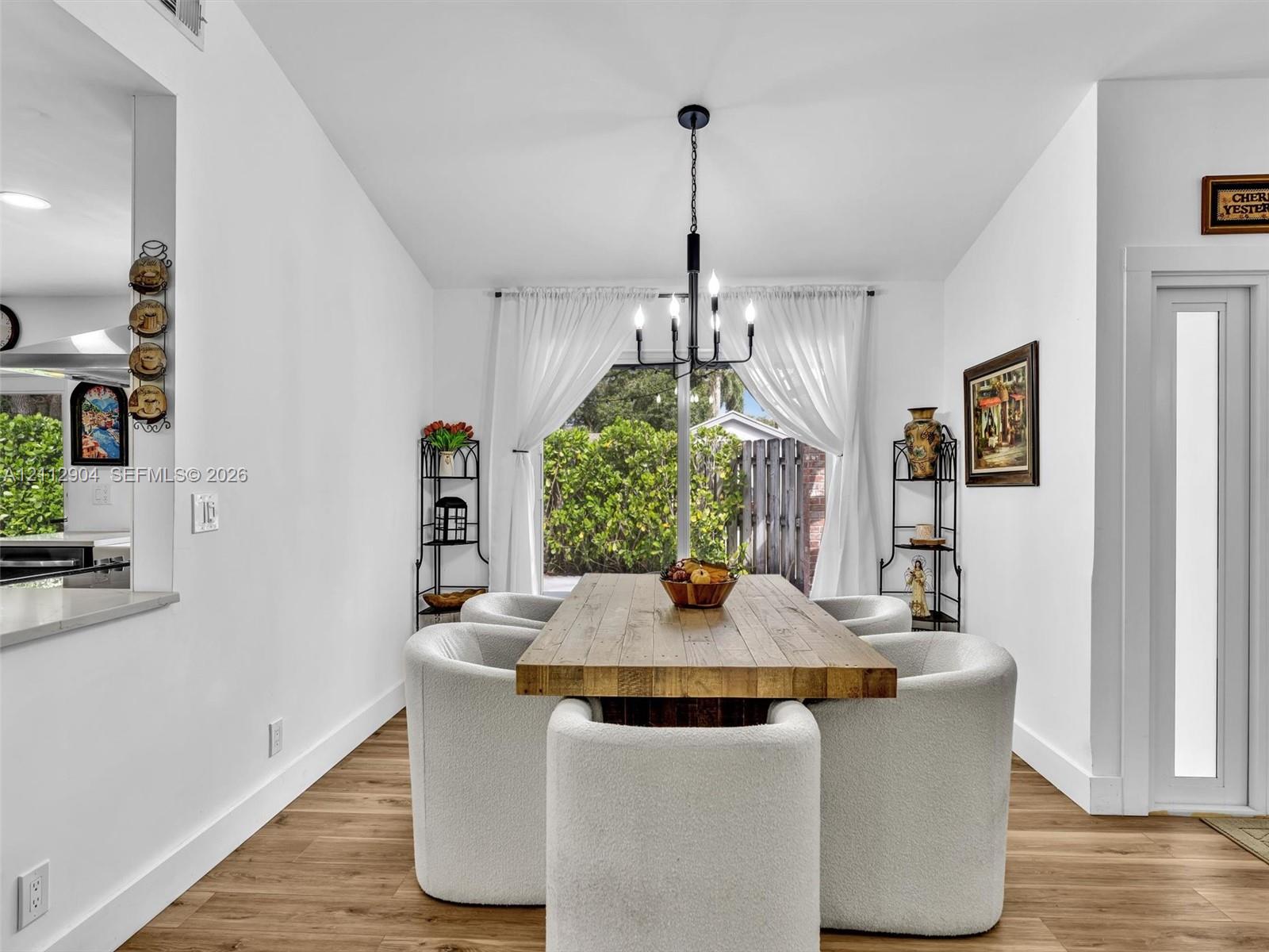 Dining area featuring wood-finish flooring, a contemporary six-arm chandelier, and sliding glass doors with direct exterior access