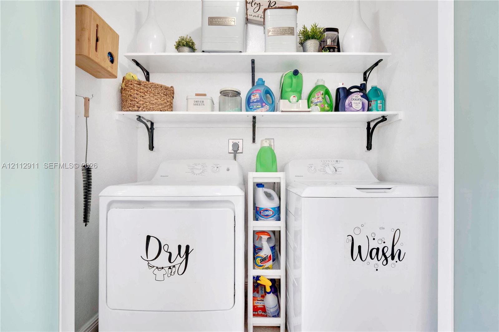 Laundry nook featuring dual-level white wall-mounted shelving with black metal support brackets