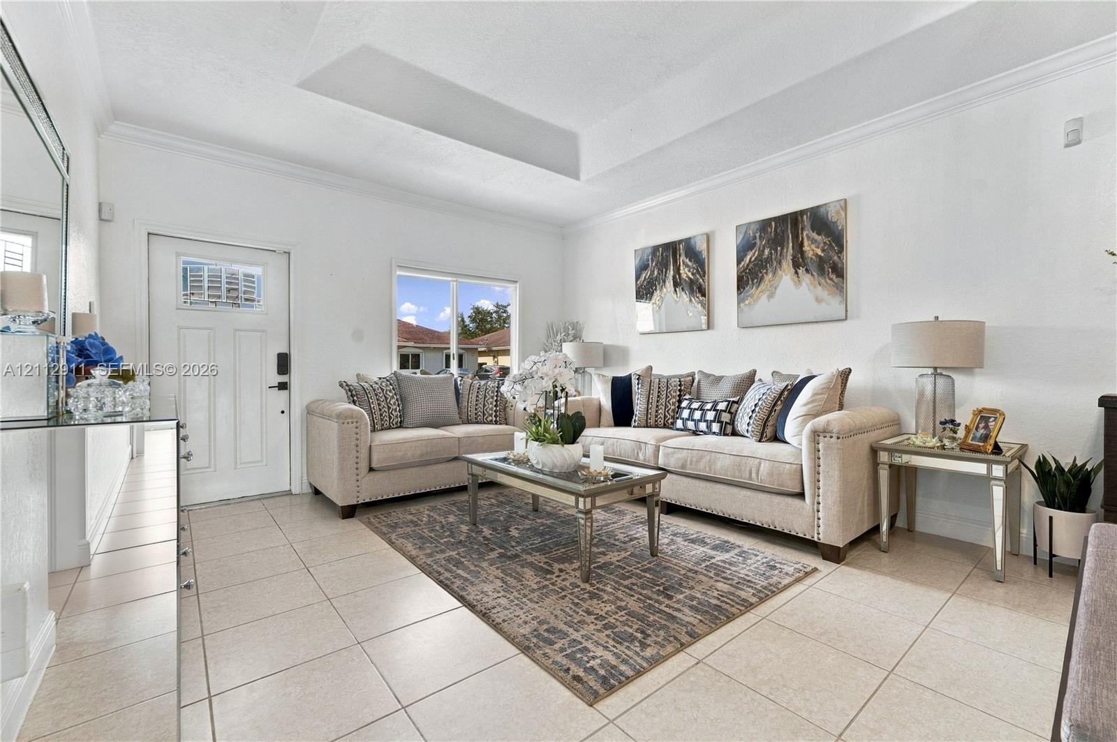 Interior space featuring ceramic tile flooring, a tray ceiling, crown molding, and a multi-panel entry door with an integrated window