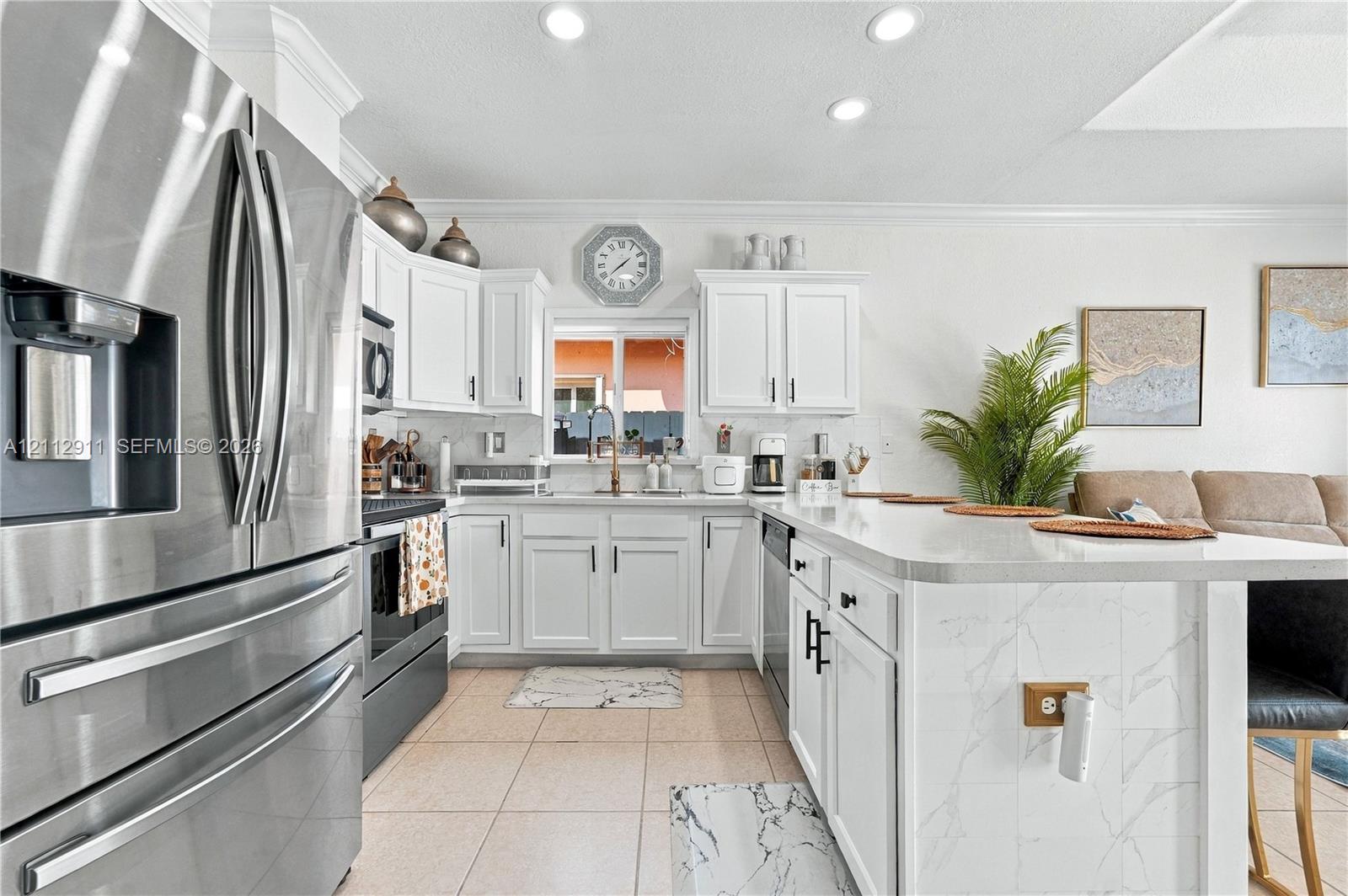 Kitchen featuring white cabinetry, stainless steel appliances, and a central island with a stone-finish countertop