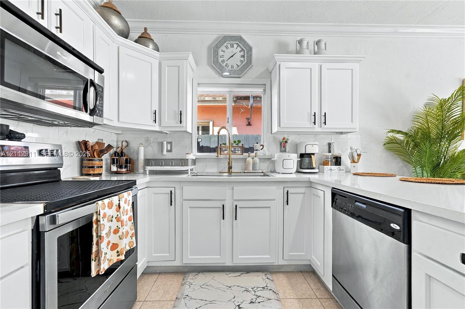 Kitchen featuring white cabinetry with matte black hardware, stone-finish countertops, stainless steel appliances, and a single-basin sink with a goose-neck faucet